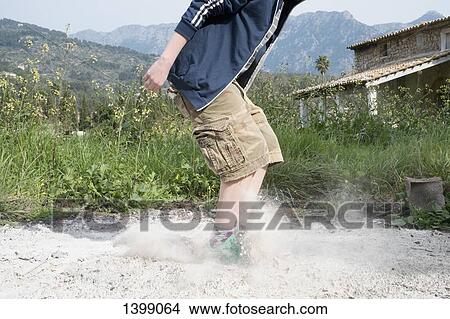Picture - Low section of boy jumping on sand outdoors. Fotosearch