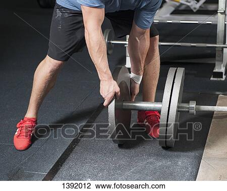 Low section of man adding weights on barbell View Large Photo Image Stock Image - Low section of man adding weights on barbell. Fotosearch