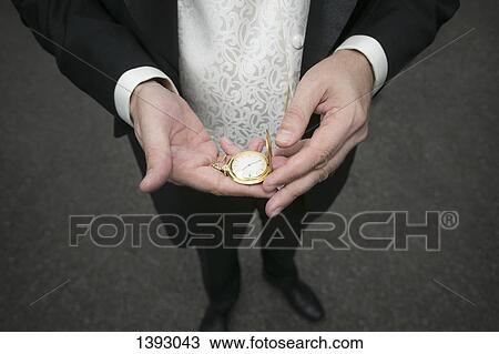 Low section of mid adult man holding pocket watch outdoors View Large Photo Image Stock Image - Low section of mid adult man holding pocket watch outdoors. Fotosearch