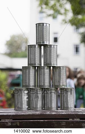 Stock Image - Metallic tin stacked on table outdoors. Fotosearch