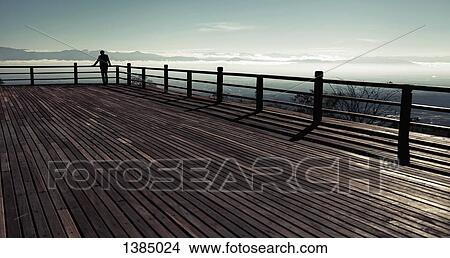 Mid distance of silhouette man looking at sea view from observation point View Large Photo Image Picture - Mid distance of silhouette man looking at sea view from observation point. Fotosearch