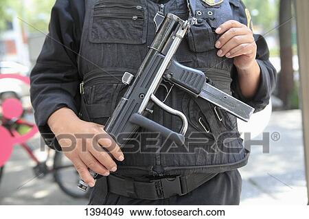 Midsection of security officer holding gun on street View Large Photo Image Stock Photo - Midsection of security officer holding gun on street. Fotosearch