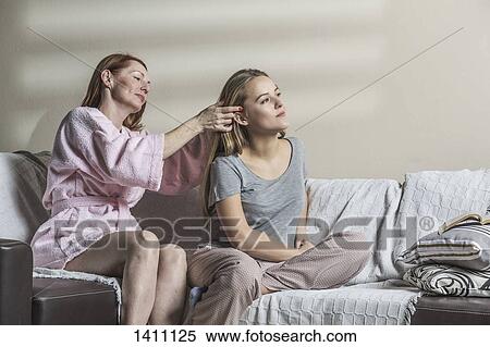 Mother making daughter's hair on sofa at home View Large Photo Image Stock Photography - Mother making daughter's hair on sofa at home. Fotosearch
