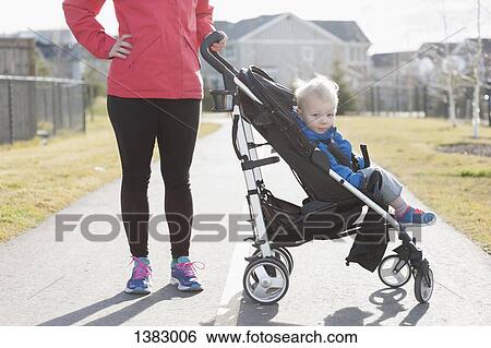 Stock Photograph - Mother with baby boy in stroller on street. Fotosearch