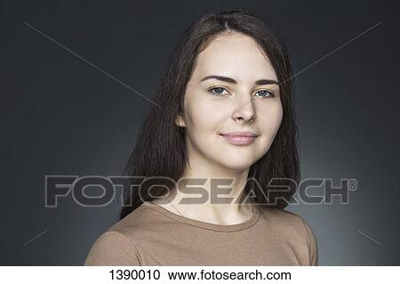 Stock Image - Portrait of beautiful young woman over gray background. Fotosearch