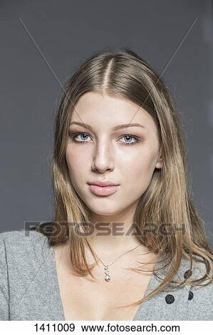 Stock Photo - Portrait of beautiful young woman against gray background. Fotosearch