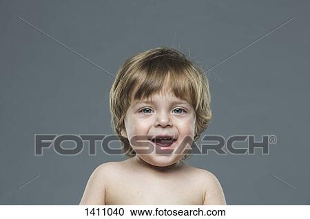 Stock Image - Portrait of cheerful boy against gray background. Fotosearch