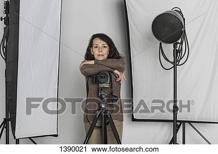 Portrait of confident mature female photographer leaning on camera tripod in photo studio View Large Photo Image Stock Image - Portrait of confident mature female photographer leaning on camera tripod in photo studio. Fotosearch