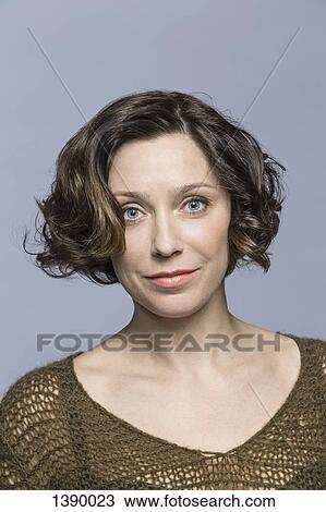 Stock Image - Portrait of confident mid adult woman over gray background. Fotosearch