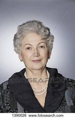 Stock Photograph - Portrait of confident senior woman over gray background. Fotosearch