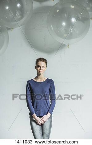 Stock Image - Portrait of confident woman standing with hands clasped against white background. Fotosearch