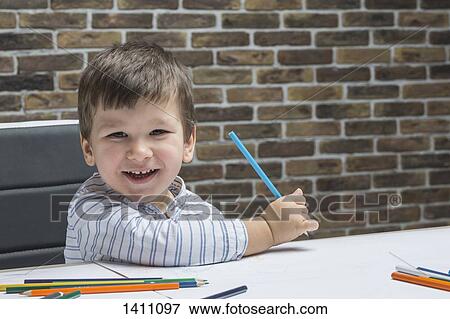 Stock Photo - Portrait of happy boy drawing at table in house. Fotosearch