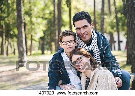 Stock Photo - Portrait of happy family sitting on in forest. Fotosearch