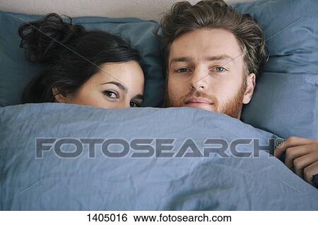 Portrait of loving young couple under duvet in bed View Large Photo Image Stock Photograph - Portrait of loving young couple under duvet in bed. Fotosearch