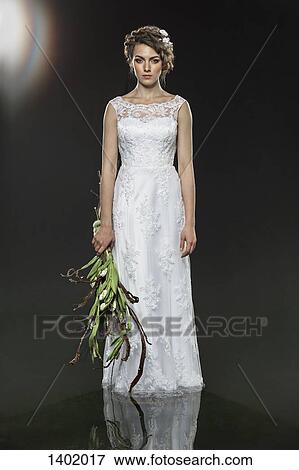 Portrait of sad young bride holding wilted bouquet while standing in water against gray background View Large Photo Image Stock Photo - Portrait of sad young bride holding wilted bouquet while standing in water against gray background. Fotosearch