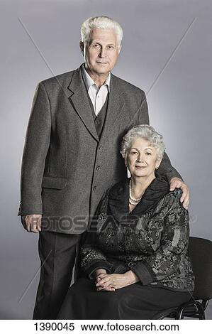Stock Photography - Portrait of senior couple against gray background. Fotosearch