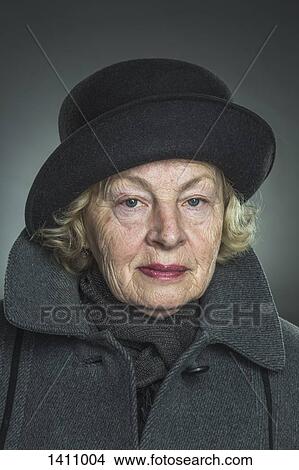 Portrait of senior woman wearing hat and jacket against gray background View Large Photo Image Picture - Portrait of senior woman wearing hat and jacket against gray background. Fotosearch