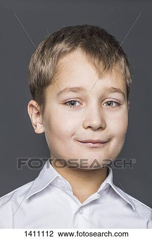 Stock Image - Portrait of smiling boy against gray background. Fotosearch