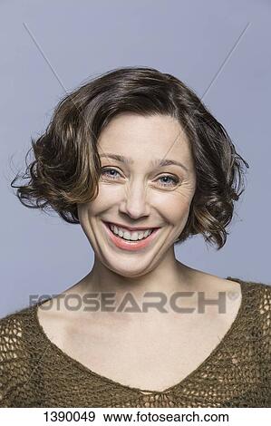 Stock Photo - Portrait of smiling mid adult woman over gray background. Fotosearch