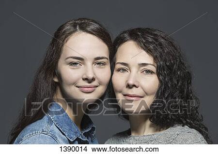 Picture - Portrait of smiling mother and daughter against over gray background. Fotosearch