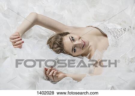 Stock Photo - Portrait of smiling young bride in wedding dress lying down. Fotosearch