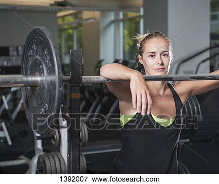 Portrait of woman leaning on barbell at gym View Large Photo Image Stock Photo - Portrait of woman leaning on barbell at gym. Fotosearch
