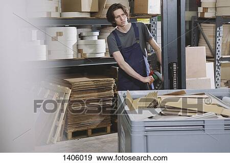 Stock Photo - Portrait of young male worker operating machine in factory. Fotosearch
