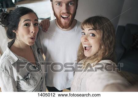 Stock Image - Portrait of young man with female friends having fun at home. Fotosearch