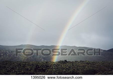 Stock Photograph - Rainbow over mountains against sky. Fotosearch