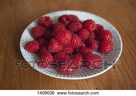 Raspberries in plate on wooden table View Large Photo Image Stock Photograph - Raspberries in plate on wooden table. Fotosearch