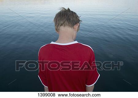 Rear view of boy standing against lake View Large Photo Image Stock Photo - Rear view of boy standing against lake. Fotosearch