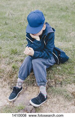 Sad boy sitting on grassy field View Large Photo Image Stock Photo - Sad boy sitting on grassy field. Fotosearch