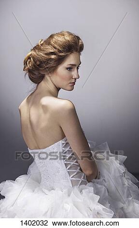 Sad young bride in wedding dress standing against gray background View Large Photo Image Stock Image - Sad young bride in wedding dress standing against gray background. Fotosearch