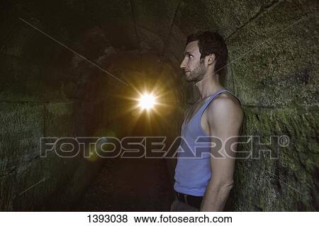 Stock Photo - Side view of man leaning on tunnel wall. Fotosearch
