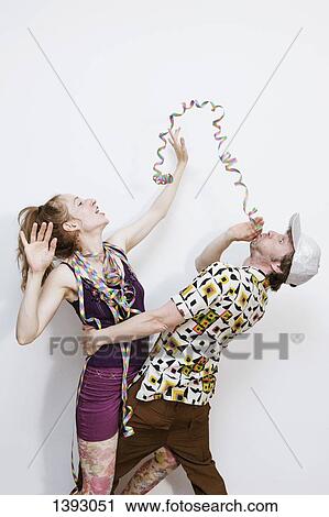 Side view of mature man blowing party ribbon towards excited woman over white background View Large Photo Image Stock Image - Side view of mature man blowing party ribbon towards excited woman over white background. Fotosearch