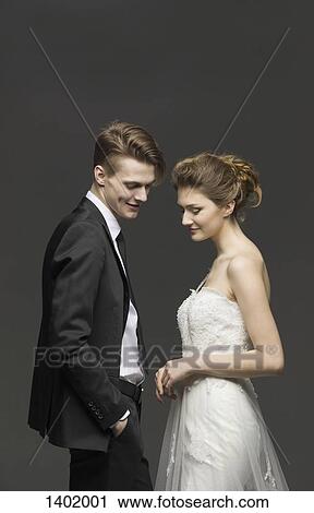 Stock Image - Side view of newly wed couple over gray background. Fotosearch