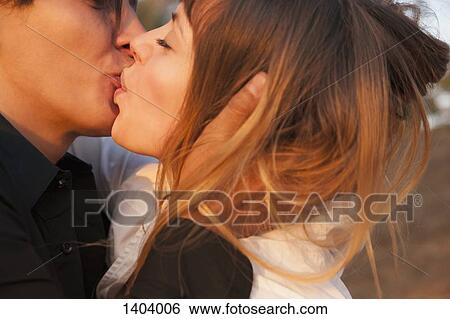 Stock Photograph - Side view of romantic couple kissing outdoors. Fotosearch