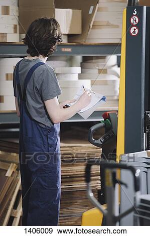 Side view of young manual worker writing on paper in warehouse View Large Photo Image Stock Photo - Side view of young manual worker writing on paper in warehouse. Fotosearch