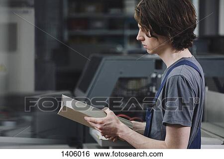 Side view of young manual worker examining cardboard sheets in factory View Large Photo Image Stock Photograph - Side view of young manual worker examining cardboard sheets in factory. Fotosearch