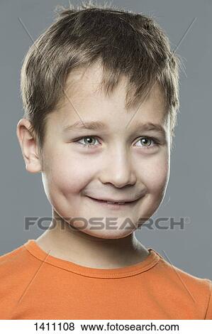Stock Photo - Smiling boy looking away against gray background. Fotosearch