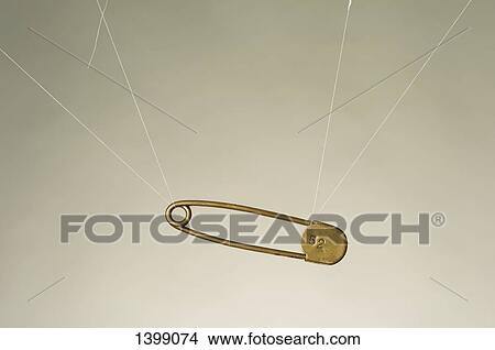 Strings tied to safety pin hanging against white background View Large Photo Image Picture - Strings tied to safety pin hanging against white background. Fotosearch