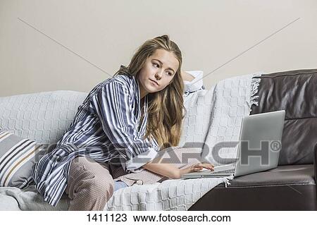 Teenage girl using laptop on sofa at home View Large Photo Image Stock Image - Teenage girl using laptop on sofa at home. Fotosearch
