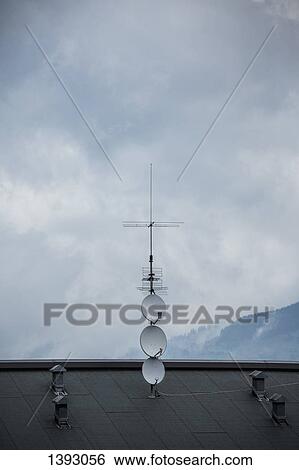 Stock Photograph - Television aerial on rooftop against cloudy sky. Fotosearch