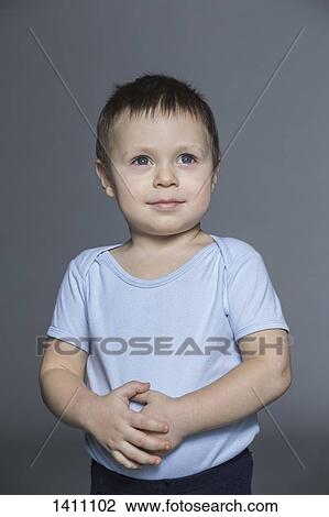 Thoughtful boy with hands on stomach standing against gray background View Large Photo Image Stock Image - Thoughtful boy with hands on stomach standing against gray background. Fotosearch