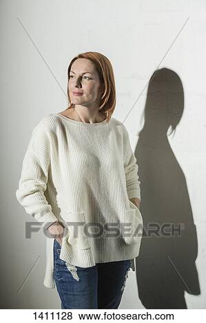 Stock Photo - Thoughtful woman standing with hands in pockets against white background. Fotosearch