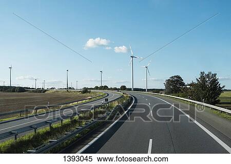 Wind turbines by empty highway View Large Photo Image Stock Photography - Wind turbines by empty highway. Fotosearch