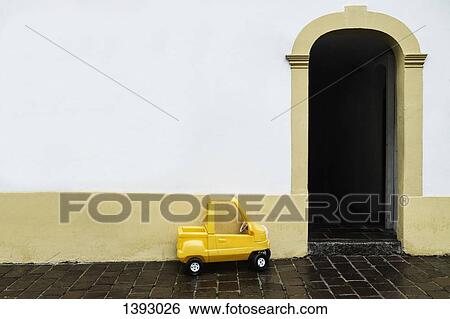 Stock Photograph - Yellow toy car by house. Fotosearch