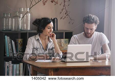 Young couple having discussion with laptop on table at home View Large Photo Image Stock Image - Young couple having discussion with laptop on table at home. Fotosearch