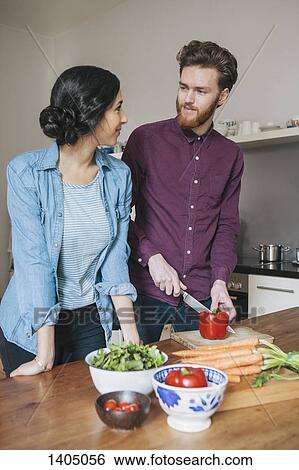 Young man chopping red bell pepper while looking at woman in kitchen View Large Photo Image Stock Photograph - Young man chopping red bell pepper while looking at woman in kitchen. Fotosearch