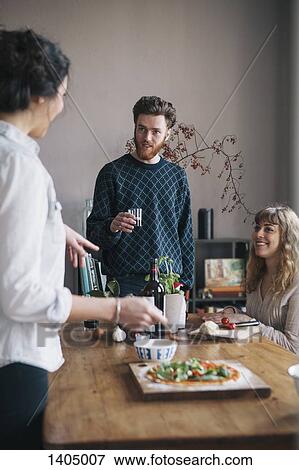 Young man with female friends talking while having breakfast at home View Large Photo Image Stock Photo - Young man with female friends talking while having breakfast at home. Fotosearch